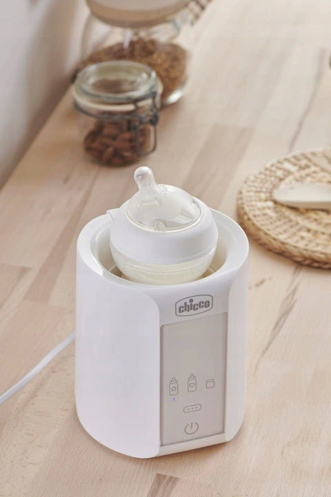 CHICCO Home Travel PODGRZEWACZ DO BUTELEK auto dom. Biały podgrzewacz butelek Chicco na stole, do domu i podróży.