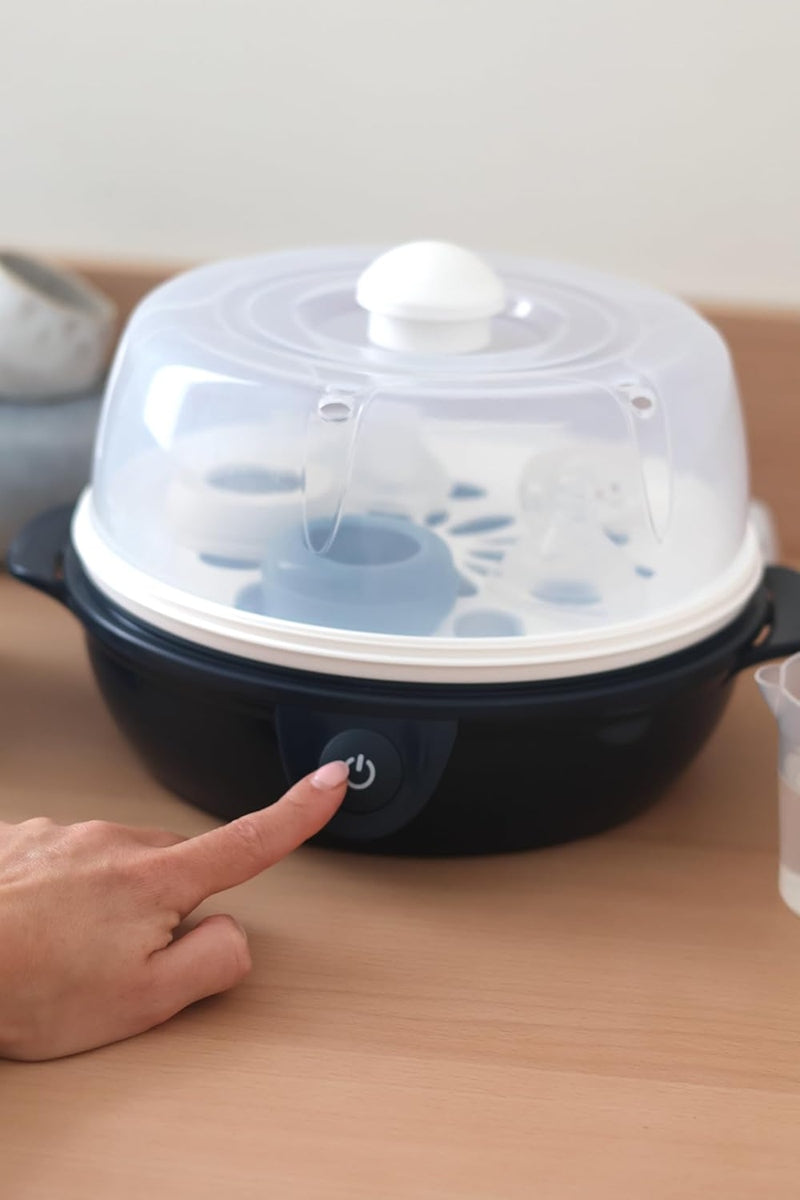 Dłoń naciska przycisk na granatowej podstawie sterylizatora Béaba Stéril'Express z niskim pojemnikiem i pokrywą.