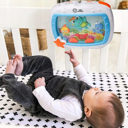 Niemowlę leży w białym łóżeczku pod pozytywką Baby Einstein Morskie Sny z figurkami morskich zwierząt.