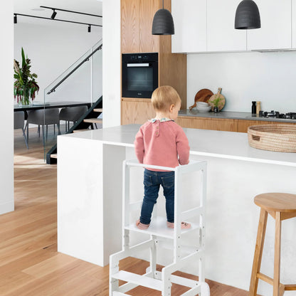 Dziecko stojące w białej wieży edukacyjnej roba 440111 WE przy kuchennym blacie.