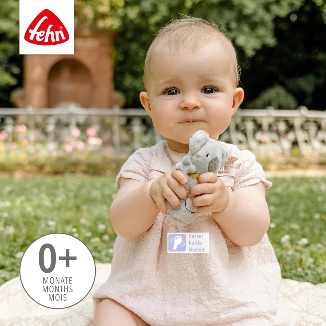 Poglądowe zdjęcie dziecka trzymającego jasnoszarego koalę oburącz na tle ogrodu.