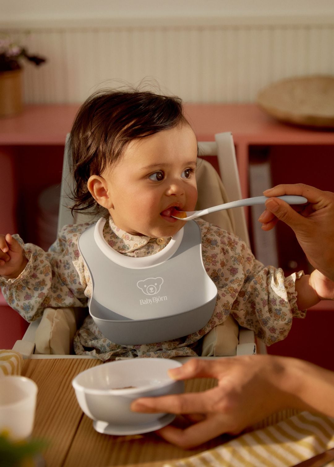Zdjęcie poglądowe dziecka karmionego szarą łyżeczką BabyBjörn przy stole.